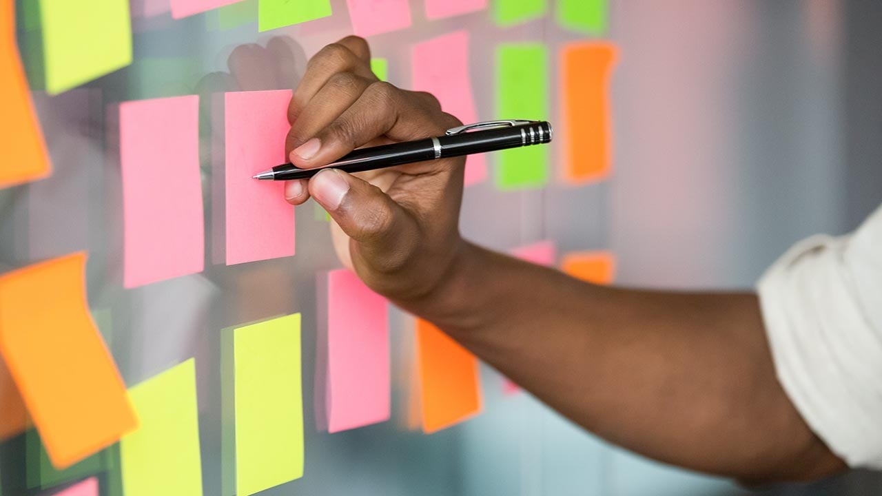 Image of a scrum master writing on a kanban board depicting agile project management.