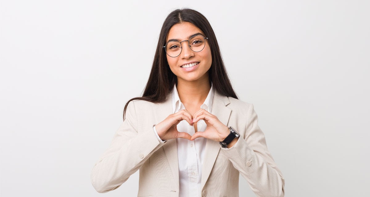 A picture of a woman smiling with her hands forming a heart