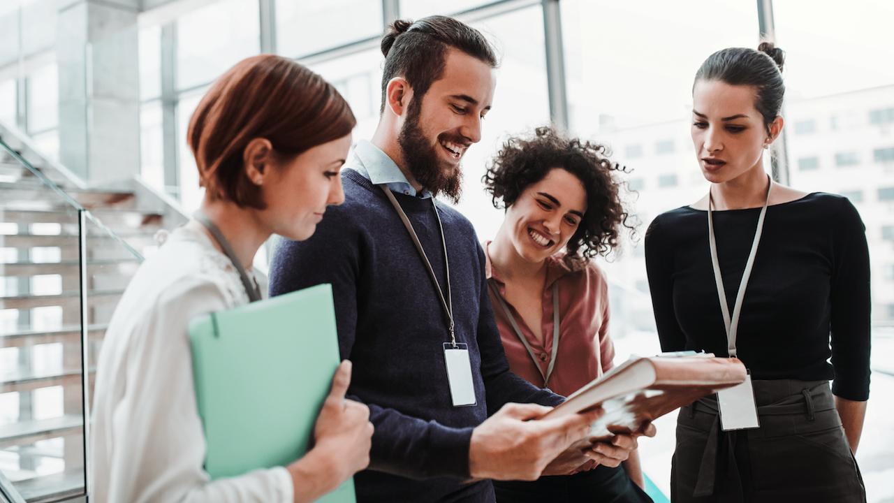 A group of colleagues happily discusses work material in person at the office