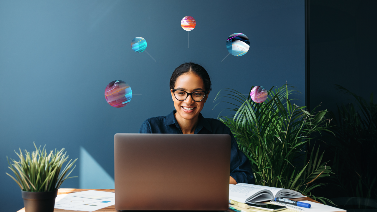 A woman at a laptop smiling with conceptual technology icons encircling her head