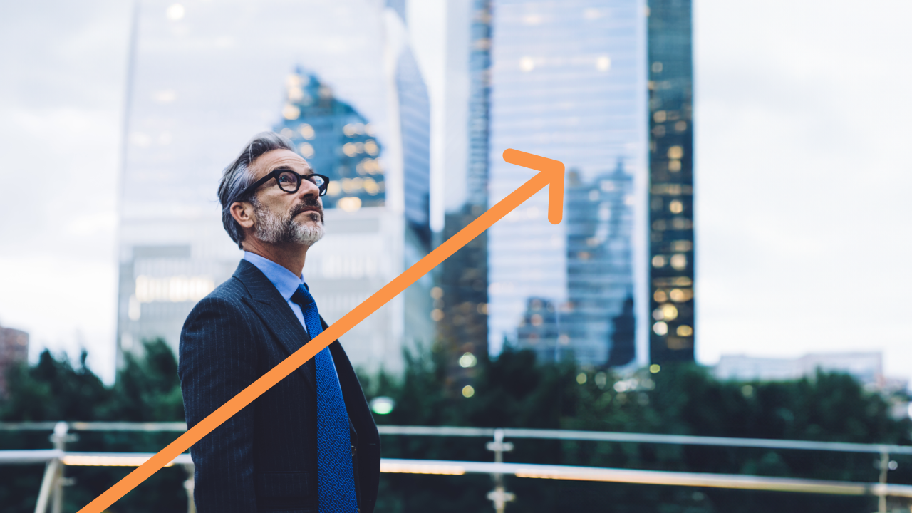 A professional man looking up in front of skyscrapers with an arrow illustration pointing upward